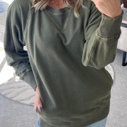 Frau in olivgrünem Sweatshirt, lässiger Stil, modisches Outfit, gemütlicher Pullover, Freizeitkleidung, Herbstmode, Innenaufnahme.