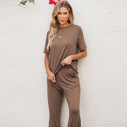 Frau in braunem, lässigem T-Shirt und Hose, steht vor hellem Hintergrund. Modetrend, Damenbekleidung, Freizeitlook, Sommeroutfit.