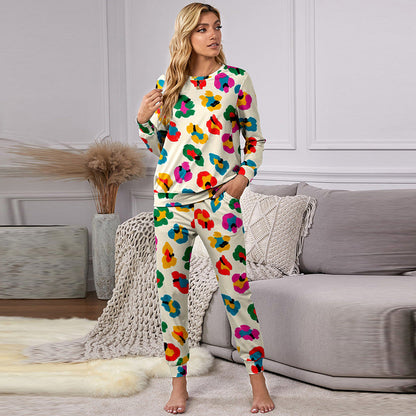 Frau in buntem Blumen-Pyjama steht in modernem Wohnzimmer, graues Sofa im Hintergrund, stilvolle Inneneinrichtung, gemütliche Atmosphäre.