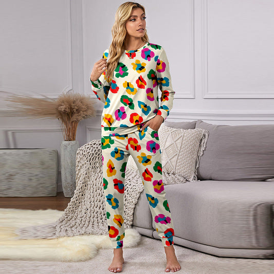 Frau in buntem Blumen-Pyjama steht in modernem Wohnzimmer, graues Sofa im Hintergrund, stilvolle Inneneinrichtung, gemütliche Atmosphäre.