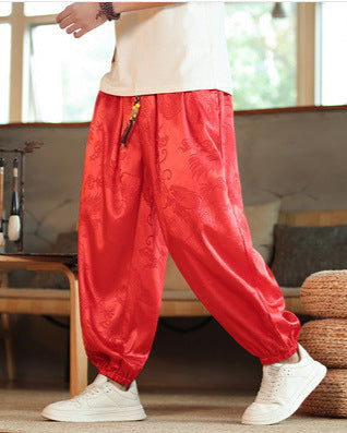 Person trägt rote, traditionelle chinesische Seidenhose mit Drachenmuster, kombiniert mit weißen Sneakers. Asiatische Mode, bequeme Kleidung.