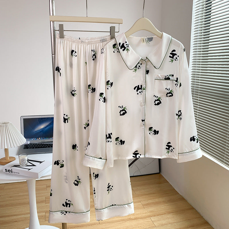 Weiße Damen-Pyjamas mit Panda-Muster, bestehend aus Hemd und Hose, auf Kleiderbügel in modernem Schlafzimmer. Bequeme Nachtwäsche, stilvolles Design.