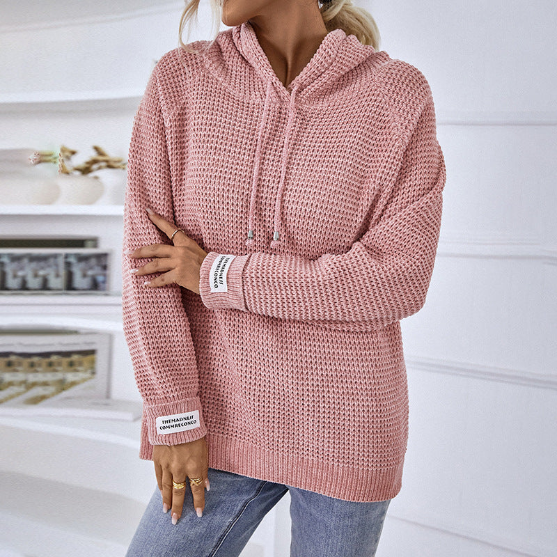 Frau trägt rosa Strickpullover mit Kapuze, lässig und modisch, ideal für Herbstmode. Perfekt kombiniert mit blauen Jeans.