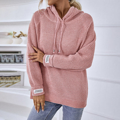 Frau trägt rosa Strickpullover mit Kapuze, lässig und modisch, ideal für Herbstmode. Perfekt kombiniert mit blauen Jeans.