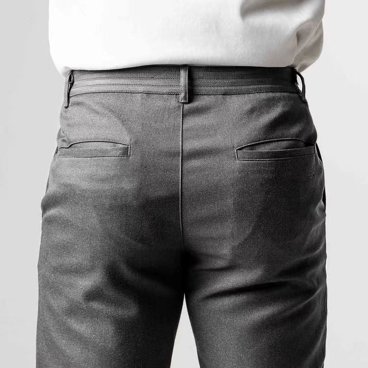 Rückansicht einer Person in grauer Anzughose und weißem Hemd. Businessmode, elegante Herrenbekleidung, formelle Kleidung.