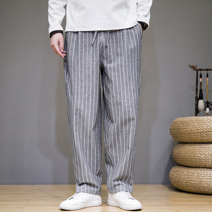 Graue gestreifte Herren-Hose, lässig geschnitten, kombiniert mit weißen Sneakers. Modetrend, Herrenbekleidung, Freizeitlook.