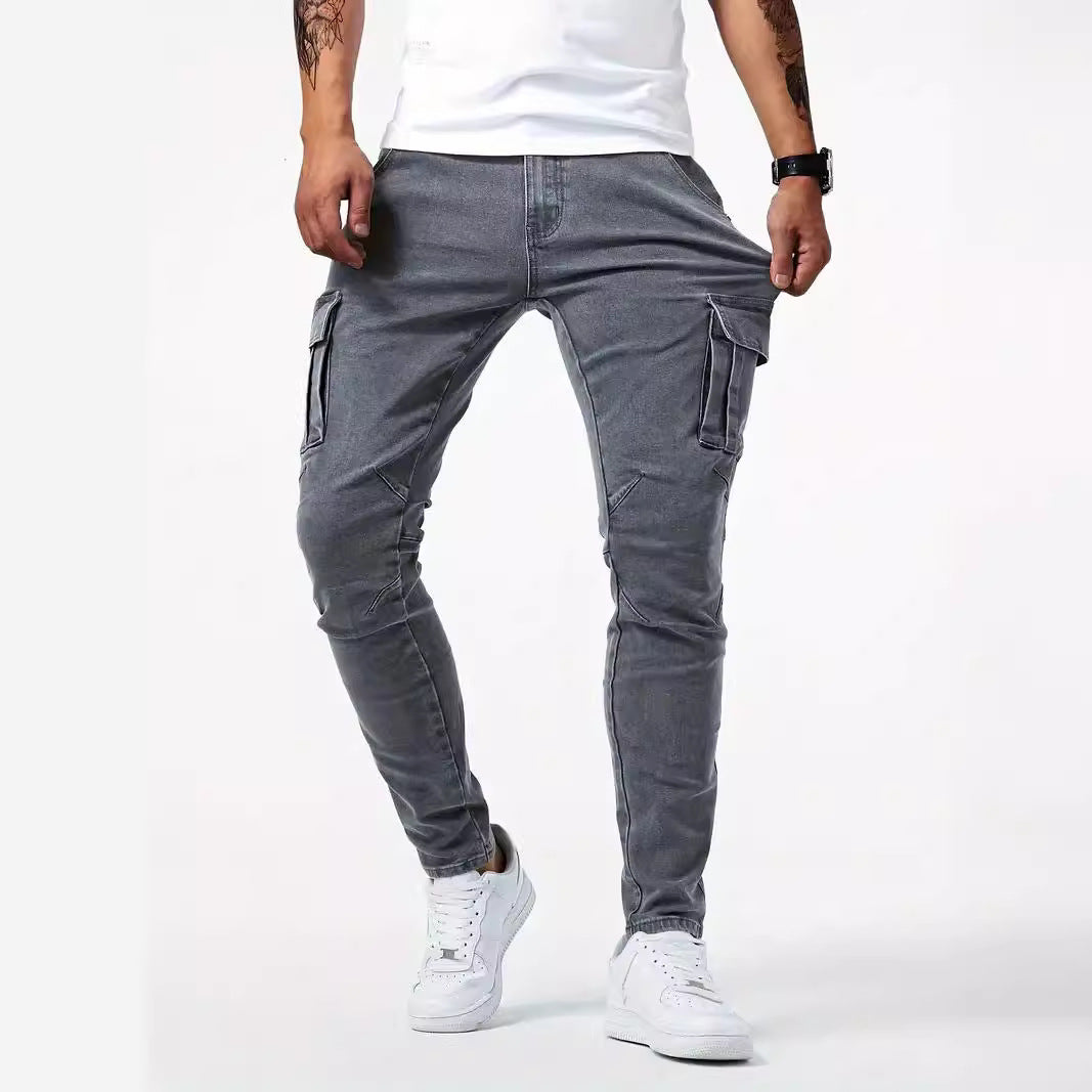 Graue Cargo-Jeans für Herren, schmal geschnitten, mit Seitentaschen, kombiniert mit weißen Sneakers und weißem T-Shirt. Ideal für lässige Outfits.