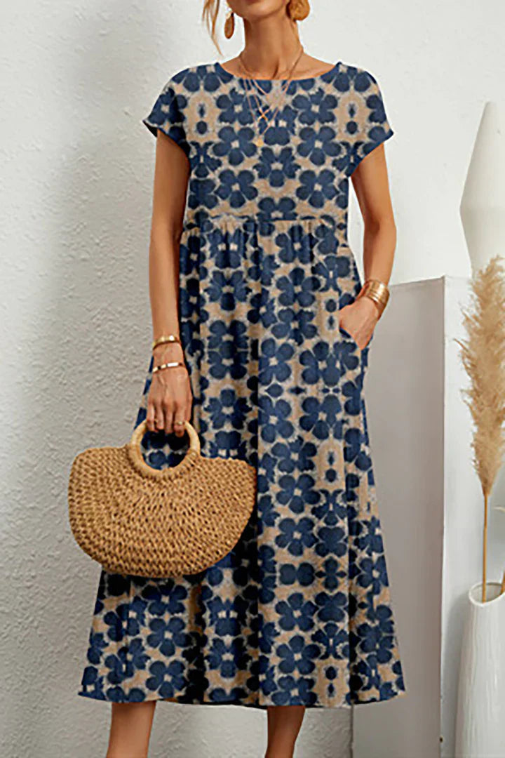 Frau in blauem, geblümtem Sommerkleid mit kurzen Ärmeln, hält eine runde Strohtasche. Modetrend, Damenmode, Sommeroutfit, Freizeitkleidung.