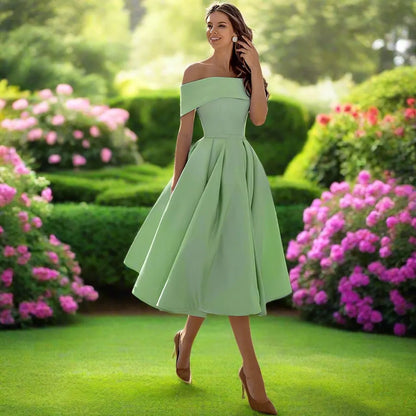 Frau in elegantem, schulterfreiem, grünem Kleid im Garten mit blühenden Hortensien, Sommermode, stilvolle Abendgarderobe, Naturkulisse.