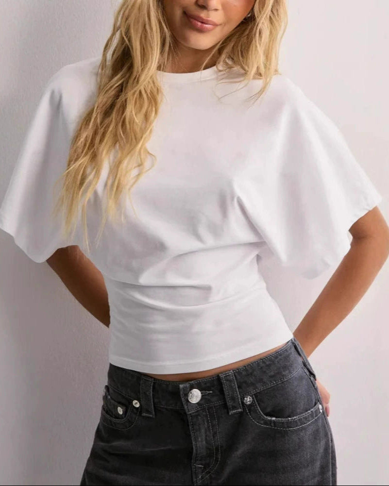 Frau in weißem T-Shirt mit weiten Ärmeln und schwarzer Jeans. Modetrend, lässiger Look, Damenbekleidung, Streetstyle.