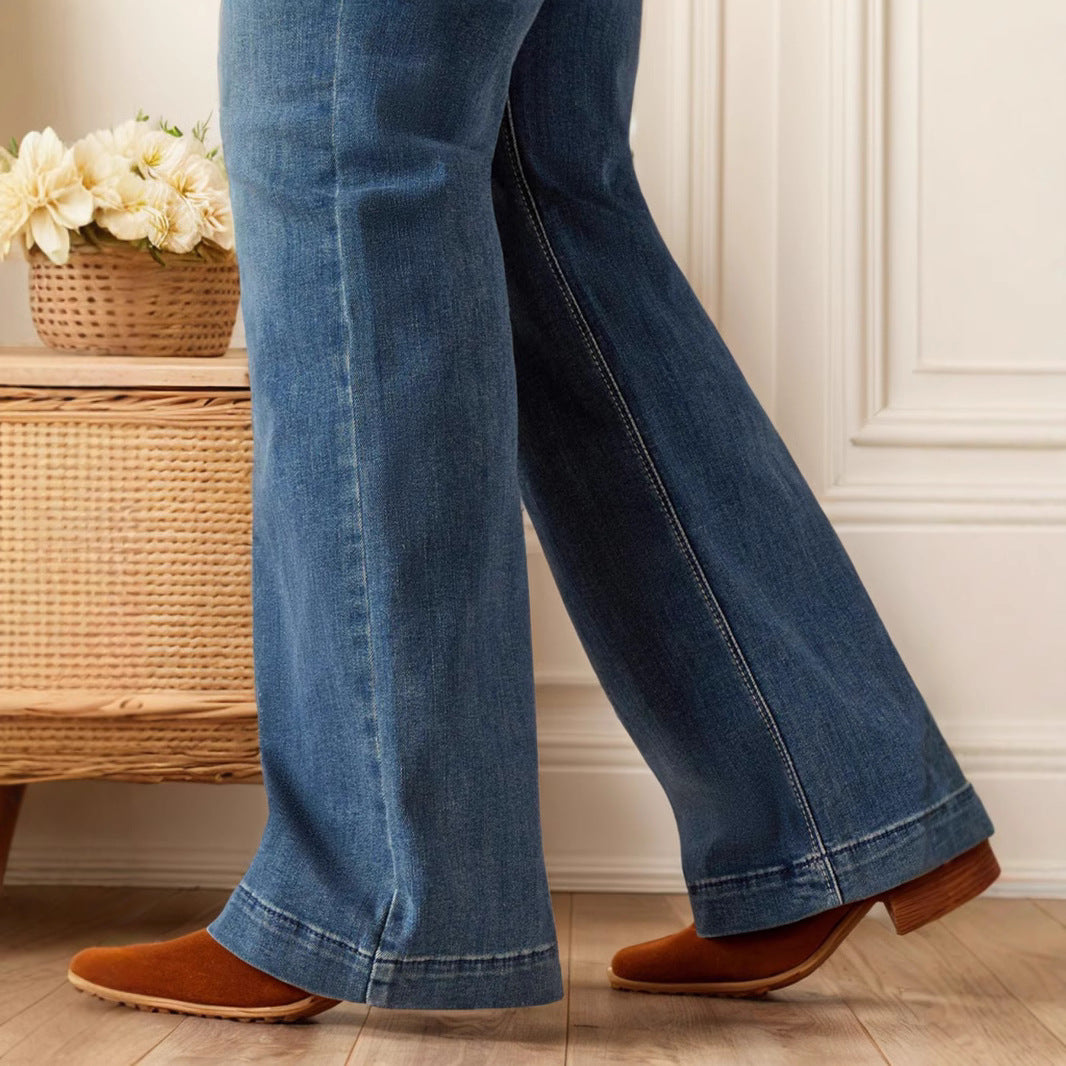 Damenjeans mit Schlag, kombiniert mit braunen Stiefeletten, vor einem Korbtisch mit weißen Blumen. Modetrend, lässiger Stil, Herbstmode.