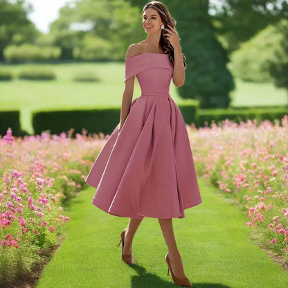 Frau in rosa, schulterfreiem Kleid spaziert durch blühenden Garten. Elegantes Sommeroutfit, Mode, Natur, Blumen, stilvoll, feminin.