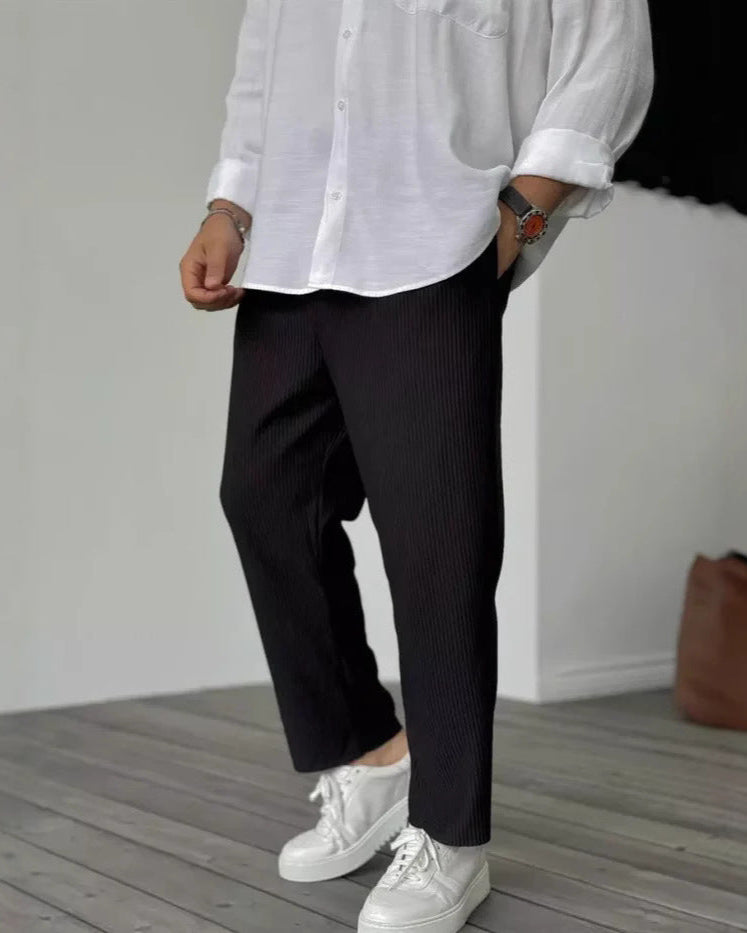 Mann in weißem Hemd und schwarzer Hose, trägt weiße Sneaker. Modischer, lässiger Look, ideal für Freizeit und Alltag.