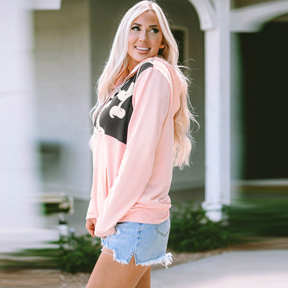 Blonde Frau in rosa Kapuzenpullover und Jeansshorts lächelt draußen. Modetrend, Freizeitkleidung, Sommeroutfit, Damenmode.