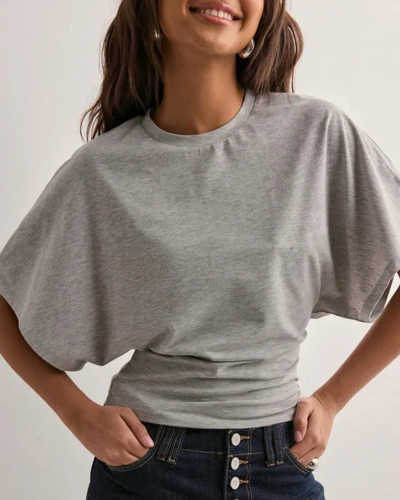 Graues T-Shirt Damenmode, lässig geschnitten, kombiniert mit dunkelblauer Jeans. Perfekt für Freizeitoutfits und modische Alltagslooks.