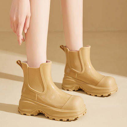 Beige Gummistiefel mit dicker Sohle, getragen von einer Person auf hellem Hintergrund. Modische, wasserdichte Stiefel für Damen.