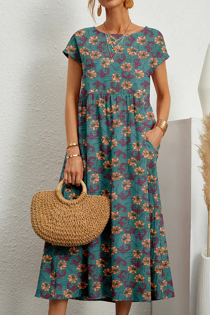 Frau in geblümtem, knielangem Kleid mit kurzen Ärmeln, hält runde Strohtasche. Sommermode, lässiger Stil, florales Muster, Damenbekleidung.