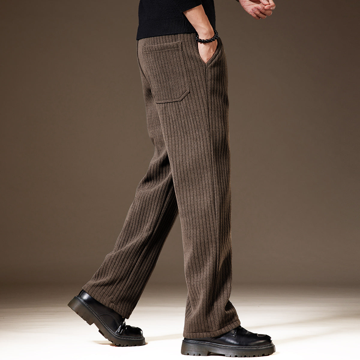 Braune Herren-Cordhose, seitlich fotografiert, mit geradem Schnitt und Taschen, kombiniert mit schwarzen Schuhen. Elegante Herrenmode.
