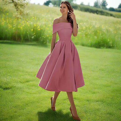 Frau in rosa, schulterfreiem Kleid auf grüner Wiese, Sommermode, elegantes Abendkleid, Naturhintergrund, stilvolle Damenbekleidung.