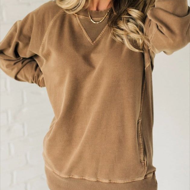 Frau in braunem Sweatshirt vor weißer Ziegelwand, lässiger Look, modische Freizeitkleidung, Herbstmode, bequemer Pullover, Damenbekleidung.