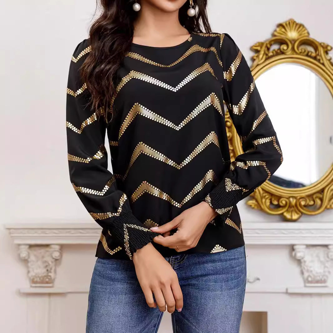 Schwarzes Langarmshirt mit goldenen Zickzack-Streifen, getragen von Frau vor Spiegel. Modetrend, elegantes Design, Damenmode, stilvoller Look.