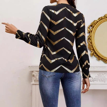 Frau in schwarzer Bluse mit goldenen Zickzack-Mustern, blaue Jeans, zeigt nach links. Elegante Mode, stilvolles Outfit, modernes Design.