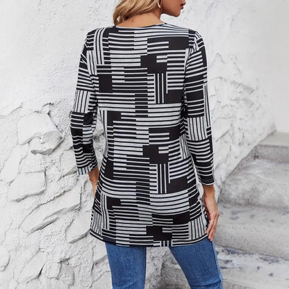 Frau in schwarz-weiß gestreiftem Langarmshirt, geometrisches Muster, Rückansicht, lässiger Stil, kombiniert mit blauen Jeans, vor weißer Wand.