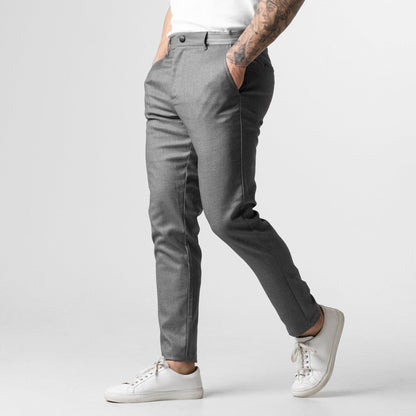 Graue Herren-Chinohose, modern geschnitten, kombiniert mit weißen Sneakern. Perfekt für stilvolle, lässige Outfits. Ideal für Modebewusste.