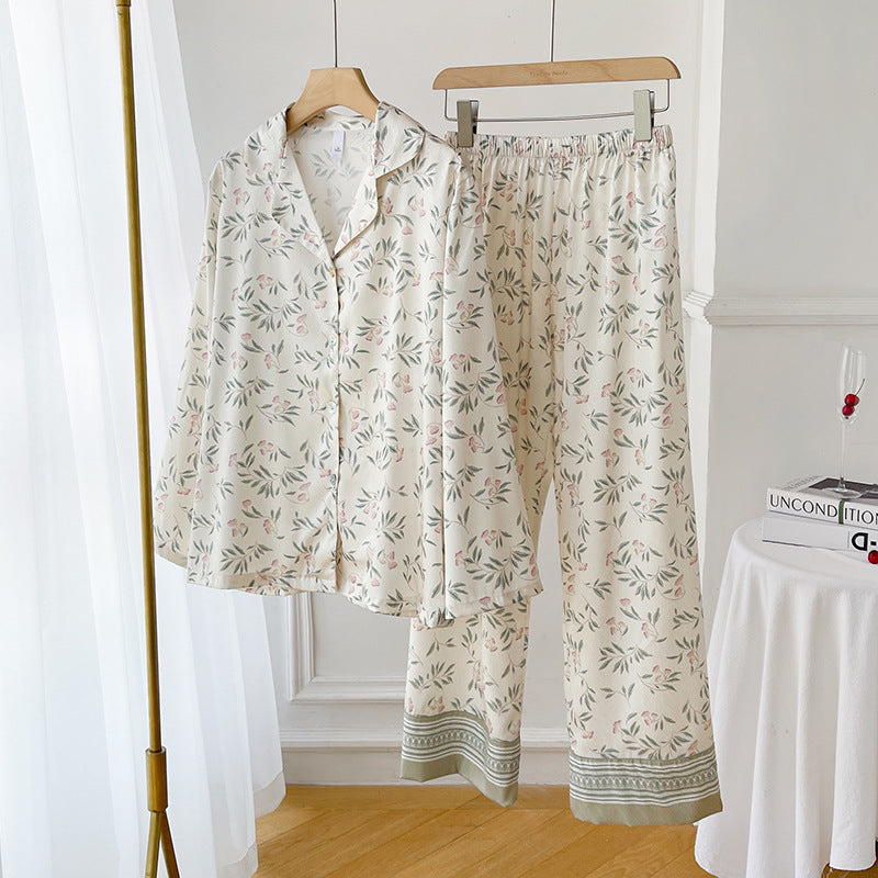 Zweiteiliges Damen-Pyjama-Set mit floralem Muster, bestehend aus langärmligem Oberteil und Hose, auf Holzkleiderbügeln in hellem Raum.