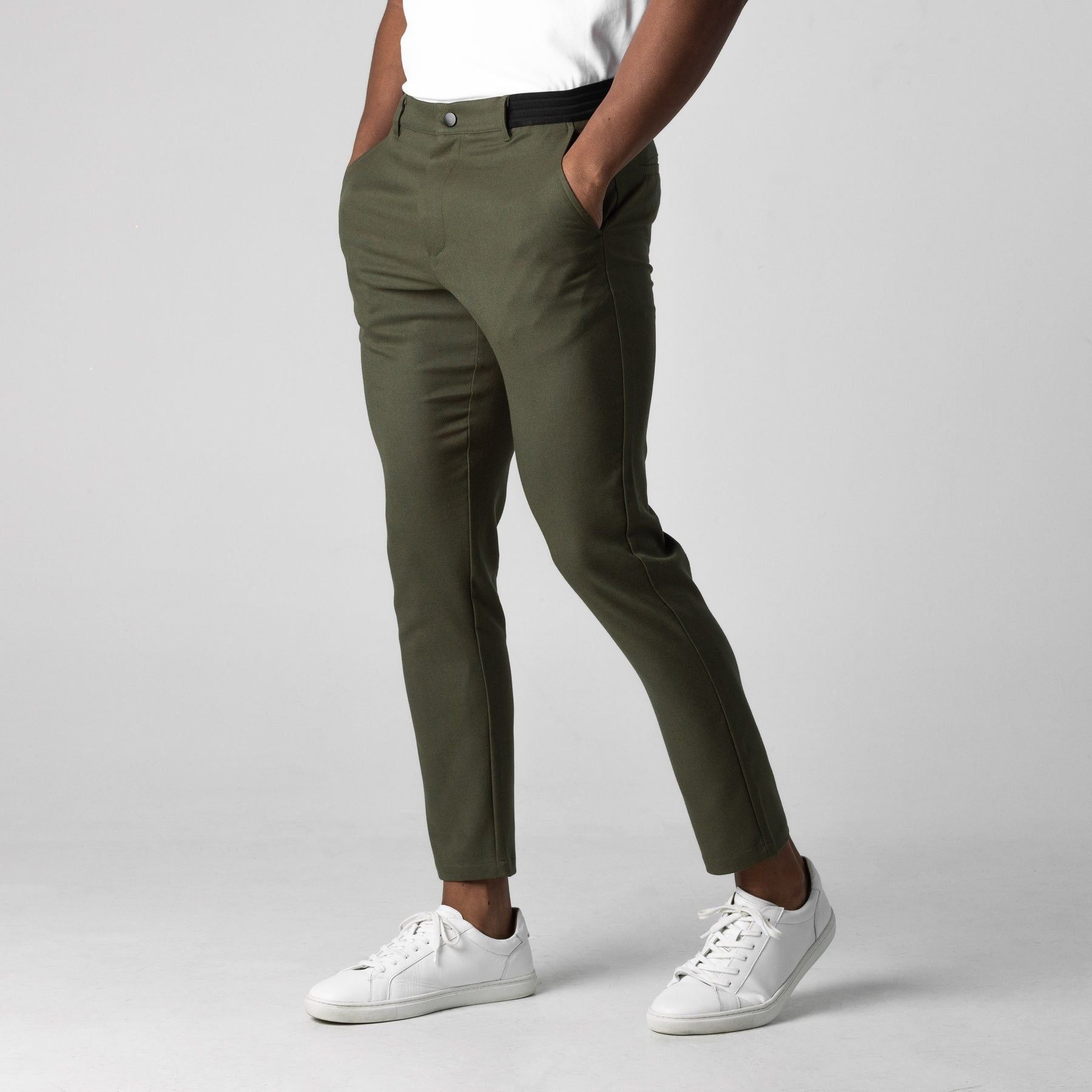Dunkelgrüne Chinohose für Herren, kombiniert mit weißen Sneakern. Modischer, lässiger Look, ideal für Freizeit und Alltag.
