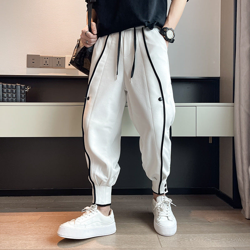 Weiße Jogginghose mit schwarzen Streifen, getragen von einer Person in weißen Sneakers. Moderne Streetwear-Mode, lässiger Stil, Innenraum.