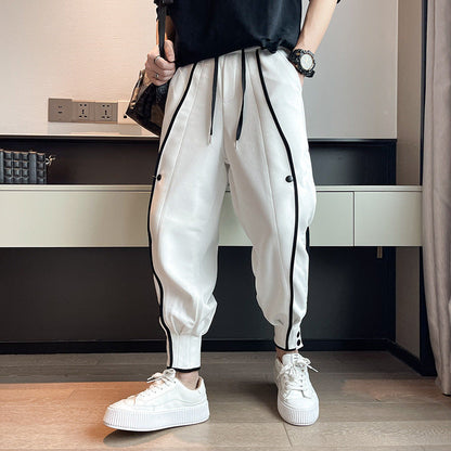 Weiße Jogginghose mit schwarzen Streifen, getragen von einer Person in weißen Sneakers. Moderne Streetwear-Mode, lässiger Stil, Innenraum.