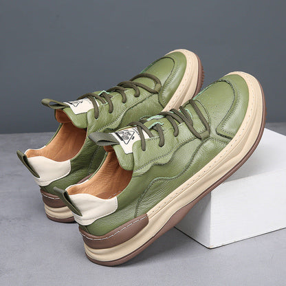 Grüne Ledersneaker mit beiger Sohle, seitlich auf grauem Hintergrund. Modische Herrenschuhe, ideal für Freizeit und Streetwear.