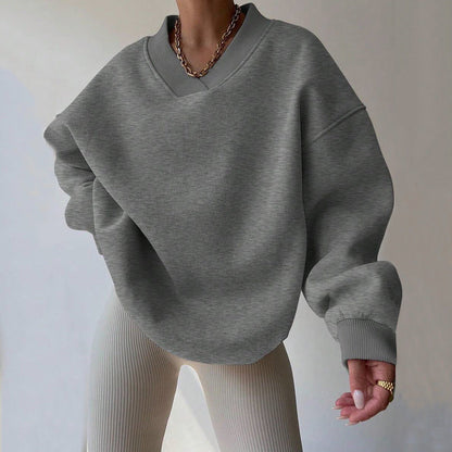 Grauer Oversize-Pullover, kombiniert mit beiger gerippter Hose. Modetrend, lässiger Stil, Damenmode, Herbstoutfit, gemütlicher Look.