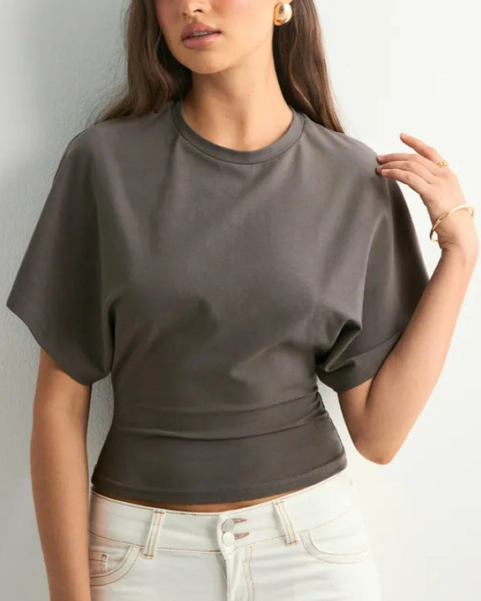 Frau trägt graues, kurzärmeliges T-Shirt und weiße Jeans. Modetrend, Damenbekleidung, lässiger Look, stilvolle Freizeitmode.