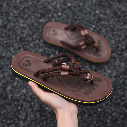 Braune Herren-Sandalen mit Fußabdruck-Design, rutschfeste Sohle und gelbem Rand, auf grauem Hintergrund. Ideal für Sommer und Strand.