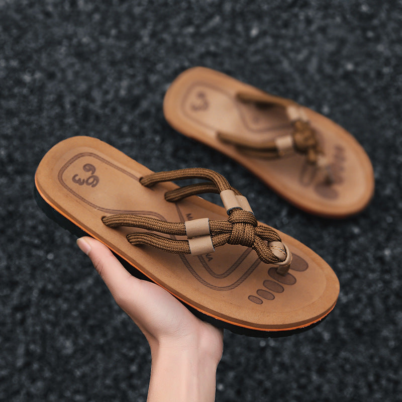 Braune Sandalen mit geflochtenen Riemen, handgehalten auf grauem Hintergrund. Bequeme Sommerschuhe, ideal für Strand und Freizeit.