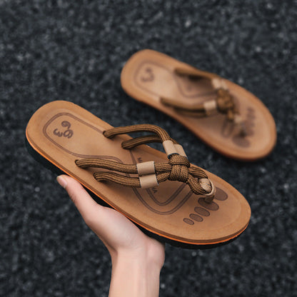 Braune Sandalen mit geflochtenen Riemen, handgehalten auf grauem Hintergrund. Bequeme Sommerschuhe, ideal für Strand und Freizeit.