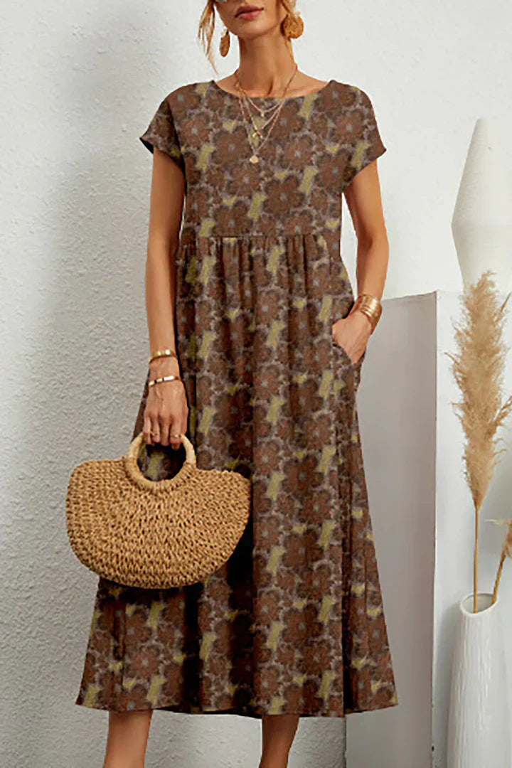 Frau in geblümtem Maxikleid mit kurzen Ärmeln, hält eine runde Strohtasche. Elegante Sommermode, Boho-Stil, ideal für Freizeit und Strand.