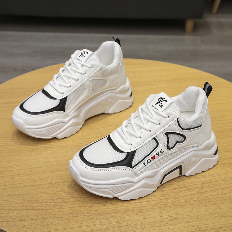 Weiße Sneaker mit schwarzem Akzent und Herzmotiv auf Holztisch, modisches Design, sportlicher Stil, bequeme Freizeitschuhe für Damen und Herren.