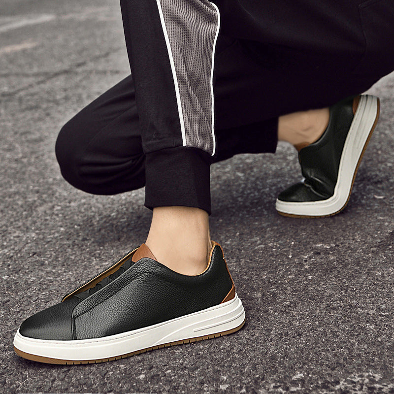 Schwarze Ledersneaker mit weißer Sohle auf Asphalt, getragen von Person in schwarzer Hose. Modische Herrenschuhe, urbaner Stil.
