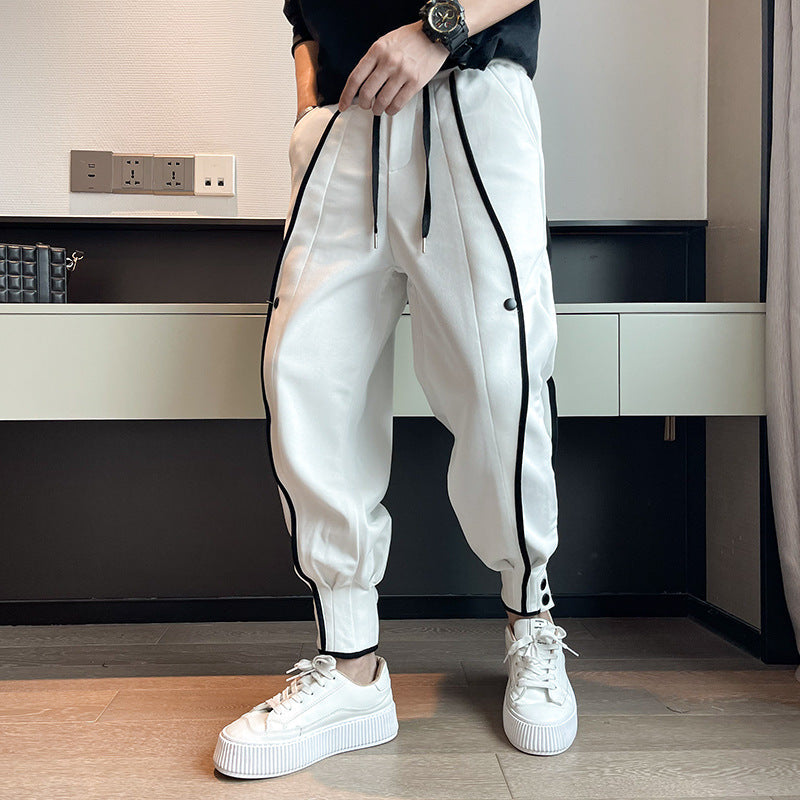 Weiße Jogginghose mit schwarzen Streifen, getragen von einer Person, kombiniert mit weißen Sneakers. Moderne Sportmode, lässiger Stil, Herrenbekleidung.