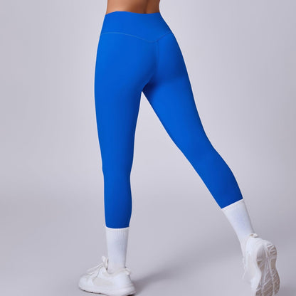 Blaue Sportleggings, Rückansicht, getragen von einer Person mit weißen Sneakers und Socken. Fitnessmode, bequeme Sportbekleidung, trendige Leggings.