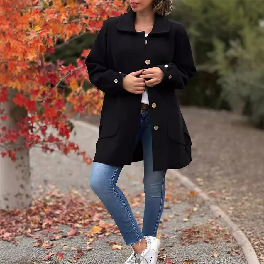 Frau in schwarzem Mantel und blauer Jeans vor herbstlichen, roten Blättern. Modetrend Herbst, Damenmode, stilvolle Herbstbekleidung.