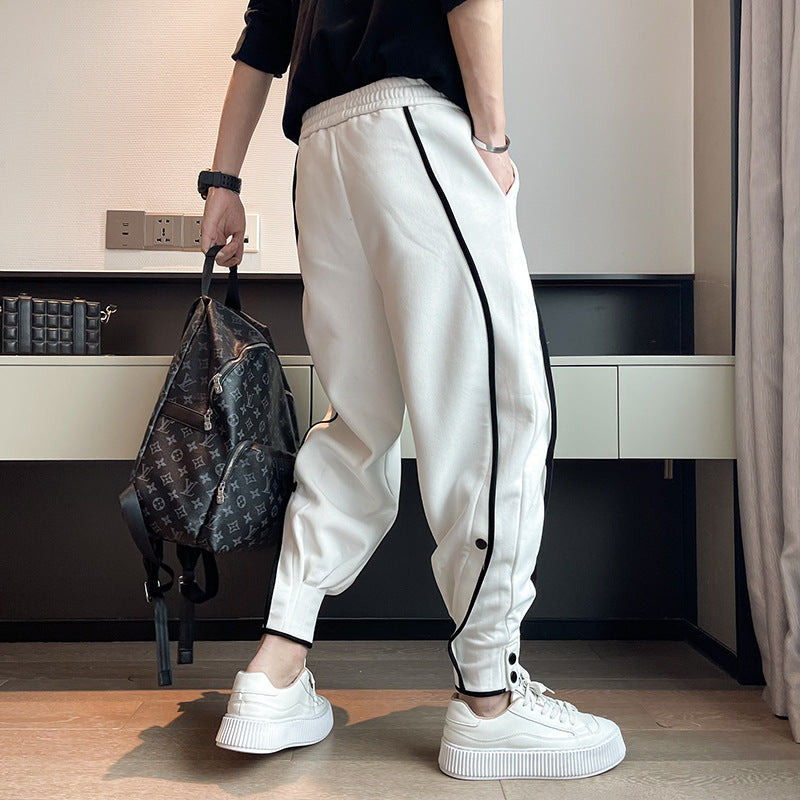 Person in weißen Jogginghosen mit schwarzen Streifen, hält einen Designer-Rucksack. Moderne Mode, lässiger Stil, trendige Sportswear.