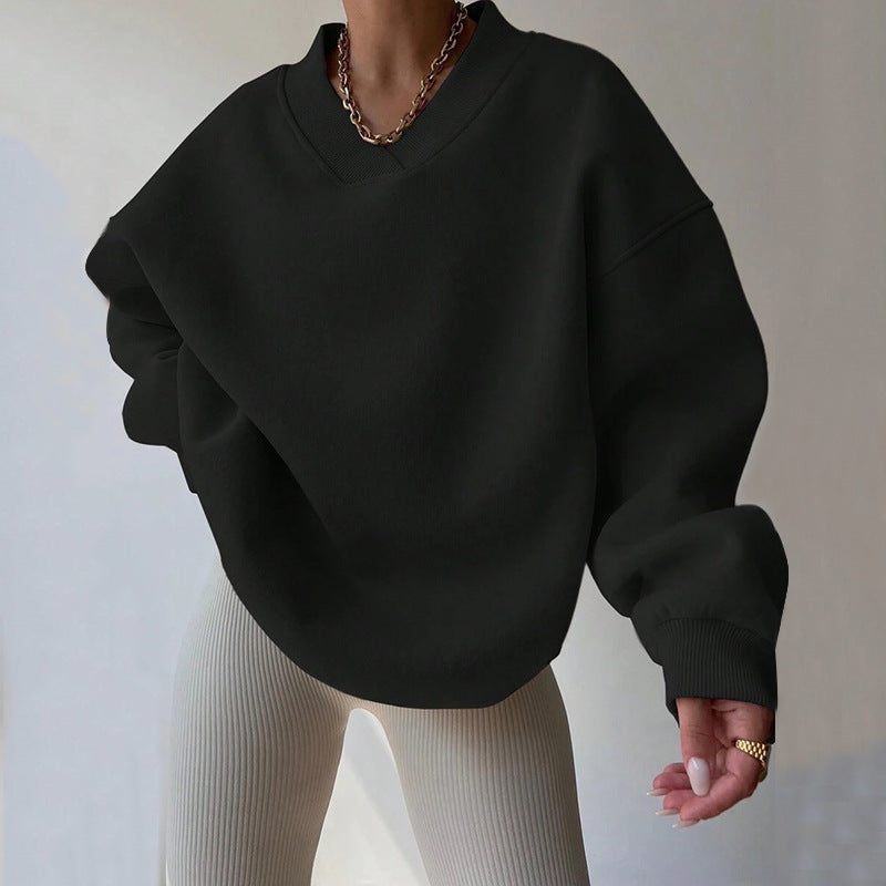 Damenmode: Schwarzer Oversize-Pullover mit V-Ausschnitt, kombiniert mit beigen gerippten Leggings. Trendiger Look, ideal für Herbstmode.
