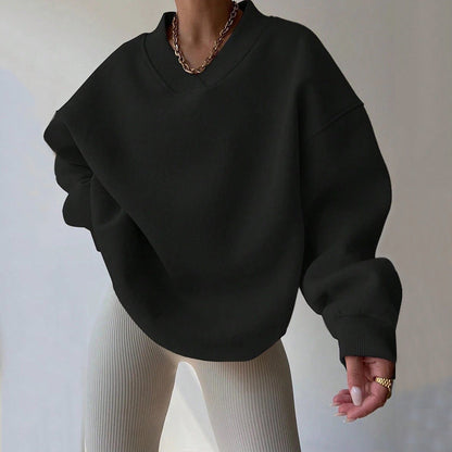 Damenmode: Schwarzer Oversize-Pullover mit V-Ausschnitt, kombiniert mit beigen gerippten Leggings. Trendiger Look, ideal für Herbstmode.