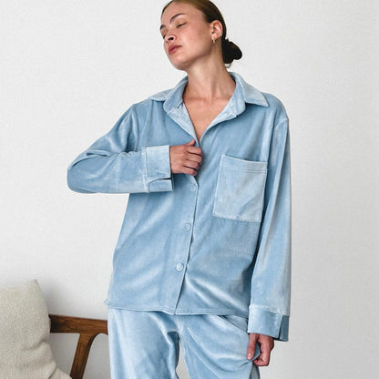 Frau in hellblauem Samt-Pyjama, entspannt posierend. Bequeme Nachtwäsche, modischer Schlafanzug, weicher Stoff, elegantes Design.