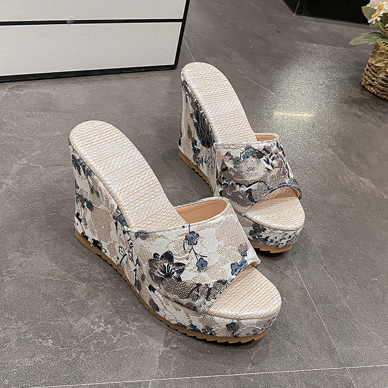 Beige Keilsandalen mit Blumenmuster, Plateauabsatz und offener Zehenpartie auf grauem Boden. Modische Damenschuhe für Sommer und Freizeit.