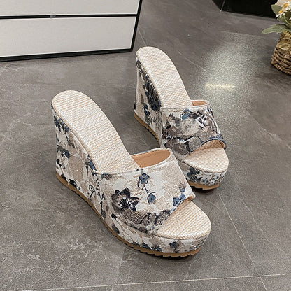 Beige Keilsandalen mit Blumenmuster, Plateauabsatz und offener Zehenpartie auf grauem Boden. Modische Damenschuhe für Sommer und Freizeit.